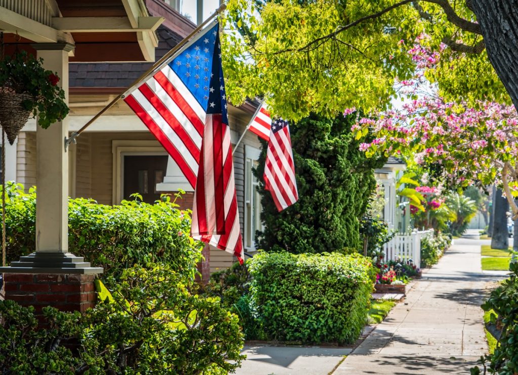 american flags on homes along sidewalk
